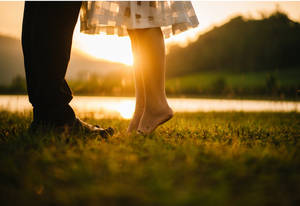 Romantic Couple Tiptoe Kiss On Grass Wallpaper