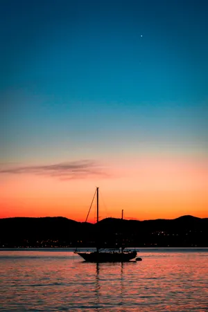Sailing Against Vibrant Twilight Sky Wallpaper
