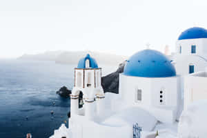 Santorini_ Blue_ Domes_ Overlooking_ Sea Wallpaper