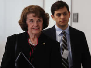 Senior U.s. Senator Dianne Feinstein Accompanied By A Bodyguard Wallpaper