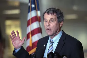 Sherrod Brown Proudly Standing Against The Backdrop Of The U.s. Flag Wallpaper