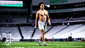 Shirtless Athlete Standingin Stadium Wallpaper