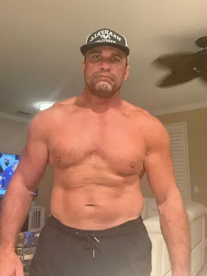 Shirtless Manin Cap Standing Indoors Wallpaper