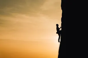 Silhouetteof Climberat Sunset Wallpaper
