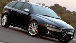 Sleek Alfa Romeo 159 On Scenic Road Wallpaper