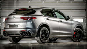 Sleek Alfa Romeo Stelvio Cruising On A Picturesque Road Wallpaper