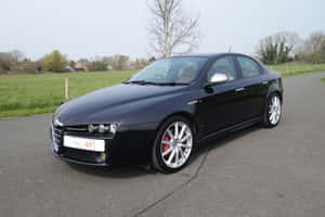 Sleek And Stylish Alfa Romeo 159 Parked Under The Night Sky Wallpaper