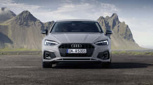 Sleek And Stylish Audi A5 On Scenic Road Wallpaper