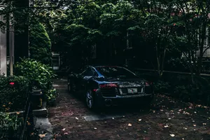 Sleek Black Car Brick Driveway Wallpaper