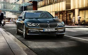 Sleek Bmw 7 Series In Motion On A Scenic Road Wallpaper