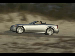 Sleek Cadillac Xlr In Vibrant City Setting Wallpaper