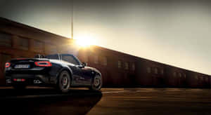 Sleek Fiat 124 Spider Cruising On The Open Road Wallpaper