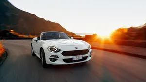 Sleek Fiat 124 Spider In A Mesmerizing Landscape Wallpaper