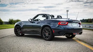 Sleek Fiat 124 Spider On A Scenic Coastal Road Wallpaper