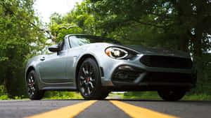 Sleek Fiat 124 Spider On An Open Road Wallpaper