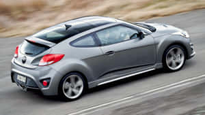 Sleek Hyundai Veloster In Motion On A Scenic Drive Wallpaper