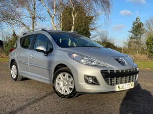 Sleek Peugeot 207 Cruising Down A Picturesque Avenue Wallpaper