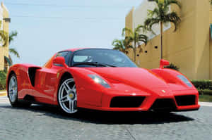 Sleek Red Ferrari Enzo On A Scenic Road Wallpaper