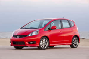 Sleek Red Honda Fit In A Coastal Setting Wallpaper