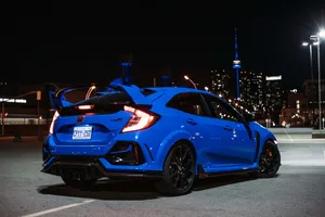Sleek Silver Hatchback Parked By The River Wallpaper
