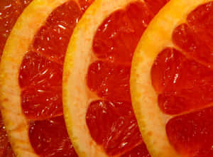 Sliced Pink Grapefruit On A Vibrant Background Wallpaper