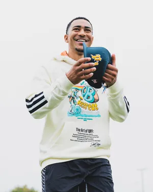 Smiling Athlete Holding Football Wallpaper