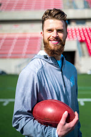 Smiling Athlete Holding Football Stadium Background Wallpaper