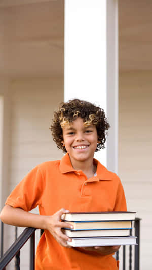 Smiling Boy Holding Books Outdoors Wallpaper