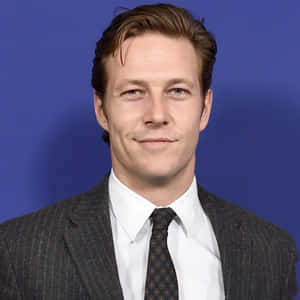 Smiling Manin Suit Against Blue Backdrop Wallpaper