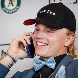 Smiling Manon Phone Wearing Bow Tieand Baseball Cap Wallpaper