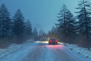 Snow-covered Road Amidst Wintery Forest Landscape Wallpaper