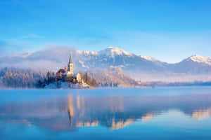 Snowed Mountain Peaks Behind Lake Bled Wallpaper