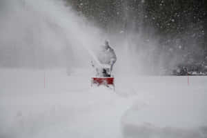 Snowplow Clearing The Road Amid Heavy Winter Snowfall Wallpaper