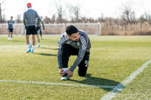 Soccer Player Tying Shoe During Training Wallpaper