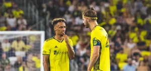 Soccer Players Discussing Strategy On Field Wallpaper