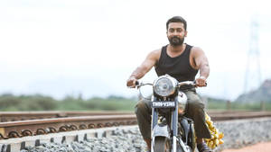 Soorarai Pottru Suriya On Motorcycle Near Tracks Wallpaper