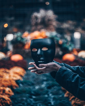 Spooky Black Mask In Hand Wallpaper