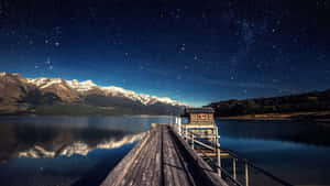 Starry Night Over Mountain Lake Pier Wallpaper