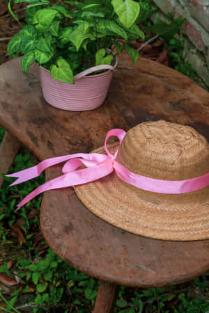 Straw Hatwith Pink Ribbonon Wooden Table Wallpaper