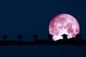 Strawberry Moon Over Silhouetted Structures Wallpaper