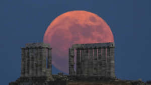 Strawberry Moon Rising Behind Ancient Columns Wallpaper