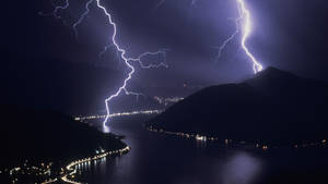 Strike Of Lightning Illuminating Coastal Mountains Wallpaper