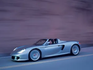 Striking Porsche Carrera Gt Roaring Along The Road Wallpaper