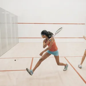 Strong Woman In Orange Playing Racquetball Wallpaper