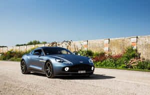 Stunning Aston Martin Vanquish In Motion On A Scenic Road Wallpaper