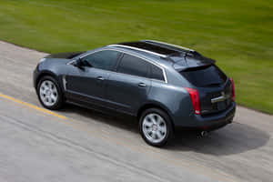 Stunning Cadillac Srx Cruising On A Picturesque Road Wallpaper