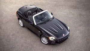 Stunning Fiat 124 Spider Cruising On Scenic Road Wallpaper