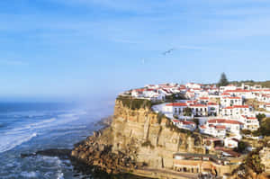 Stunning View Of The Rocky Shoreline And Waves At Portuguese Beach Wallpaper