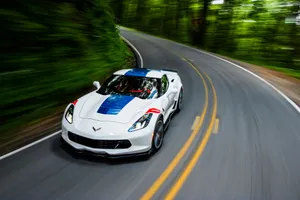 Stunning White Chevrolet Corvette Grand Sport Cruising On The Road Wallpaper