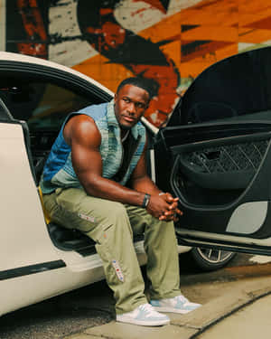 Stylish Man Seated Nextto Car Wallpaper